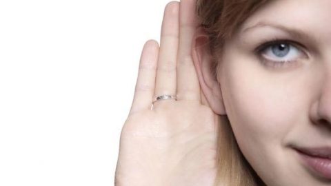 Woman listening for noise with hand behind ear