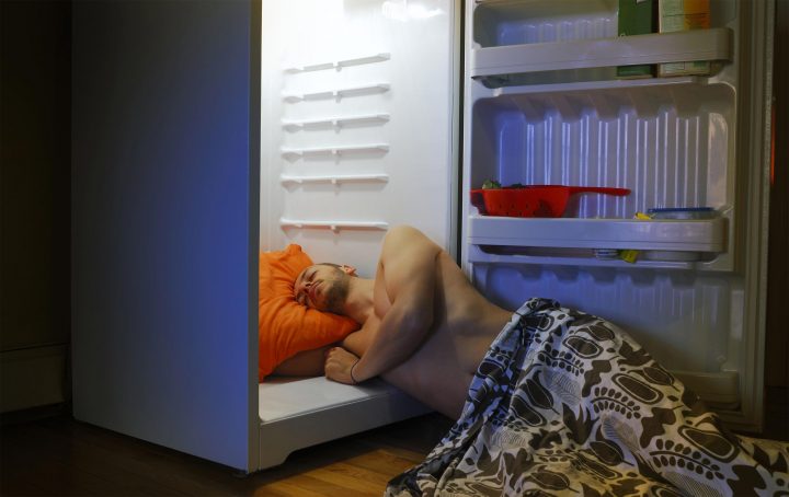 Man sleeping with his head in a refrigerator